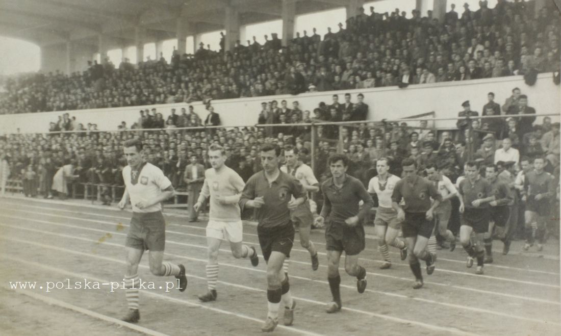 29 NËNTOR 1953. Shqipëria – Polonia, 2-0. Tribuna qendrore klasike dhe historike e stadiumit kombëtar “Qemal Stafa” që nuk është më. Skuadrat duke hyrë në fushën e ndeshjes. Djathtas Fagu, Vogli, Boriçi, Vila, Jareci, Resmja.