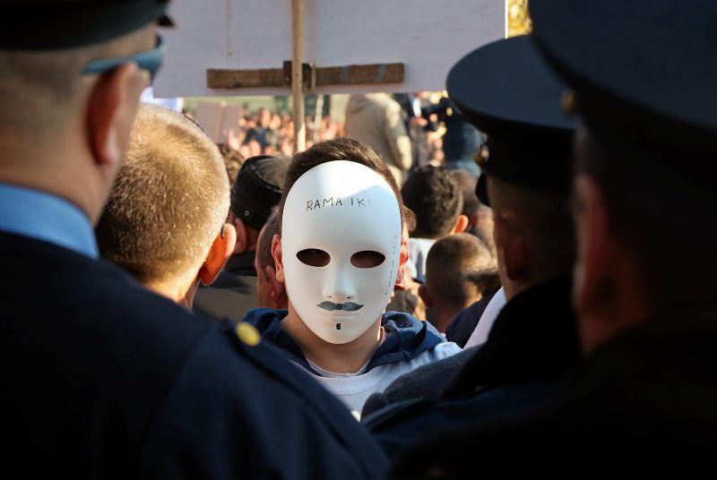 An Albanian opposition Democratic Party supporter, centre, wears a mask, during a rally in front of the Parliament building, in Tirana, Albania, Thursday, Dec. 17, 2015. to protest against government’s links to crime, corruption and taking the country into poverty, (AP Photo/Hektor Pustina)