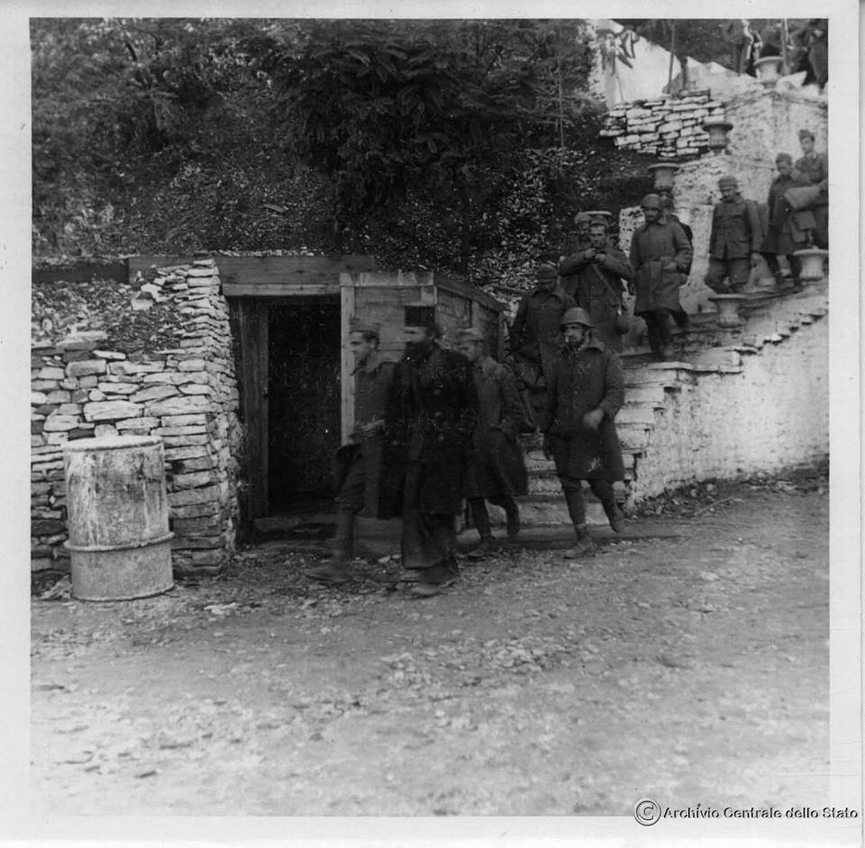 1940-1941: Robër grekë të luftës, të shoqëruar nga një prift orthodoks duke kaluar nëpër qytetin e Gjirokastrës. Marrë nga arkivat italiane. 