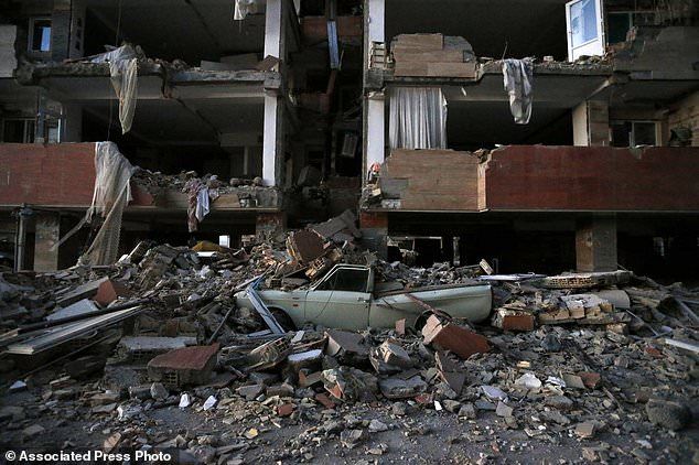 In this photo provided by the Iranian Students News Agency, ISNA, a car lays smashed by debris from the earthquake at the city of Sarpol-e-Zahab in western Iran, Monday, Nov. 13, 2017. A powerful earthquake shook the Iran-Iraq border late Sunday, killing more than one hundred people and injuring some 800 in the mountainous region of Iran alone, state media there said. (Pouria Pakizeh/ISNA via AP)