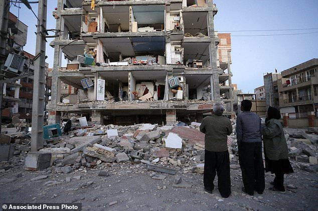In this photo provided by the Iranian Students News Agency, ISNA, people look at destroyed buildings after an earthquake at the city of Sarpol-e-Zahab in western Iran, Monday, Nov. 13, 2017. A powerful earthquake shook the Iran-Iraq border late Sunday, killing more than one hundred people and injuring some 800 in the mountainous region of Iran alone, state media there said. (Pouria Pakizeh/ISNA via AP)