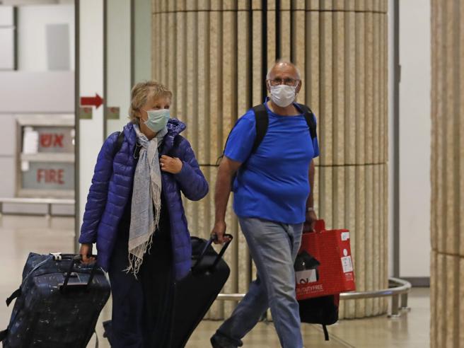 Passengers wearing protective masks walk at the arrival hall of Ben Gurion International Airport on February 22, 2020. - Israel refused to allow some 200 non-Israelis to disembark from a plane which arrived from South Korea, as part of measures against the new coronavirus, the health ministry said. It said the plane was made to return to South Korea, after the 12 Israeli passengers on board were taken away in ambulances waiting at Tel Aviv to be quarantined. (Photo by Ahmad GHARABLI / AFP)