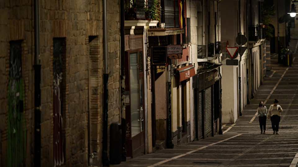 Residents wearing face protection walk along an empty Javier street, in Pamplona, northern Spain, Saturday, Oct. 24, 2020, as new measures against the coronavirus began in the Navarra province where all bar and restaurants are closing for 15 days since last October 23. (AP Photo/Alvaro Barrientos)