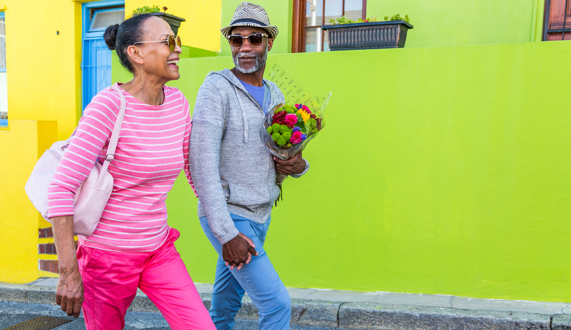 Senior couple walking past colourful houses in cape town