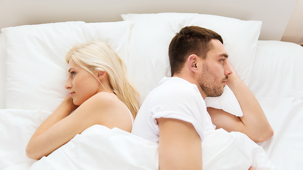 people, relationship difficulties, conflict and family concept - unhappy couple lying back to back in bed at home