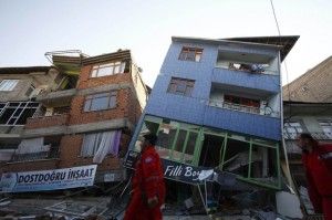 Rescue workers walk past damaged buildings in Ercis, near the eastern Turkish city of Van