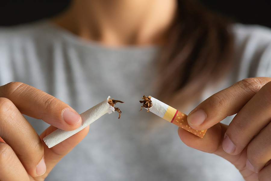 World No Tobacco Day, May 31. STOP Smoking. Close up woman hand breaking, crushing or destroying cigarettes on black background.