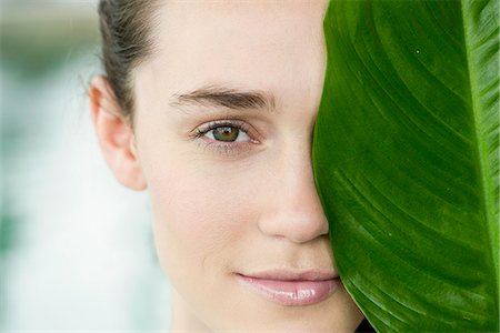 632-09021415 © Masterfile Royalty-Free Model Release: Yes Property Release: Yes Young woman holding large leaf in front of her face and smiling