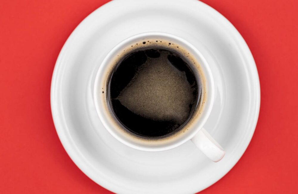 coffee-cup-saucer-red-background-flat-lay-1-1000x650